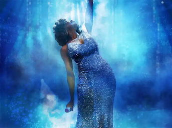 A picture of a woman in a beautiful dress as Whitney on satge.\