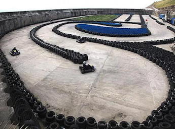 Formulakart circuit delimited by car tyres. 3 karts competing o the circuit.
