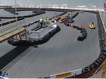 People dring karts, daytime, with the sea on the background.