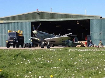 Image of a spitfire in front an opened hangar.