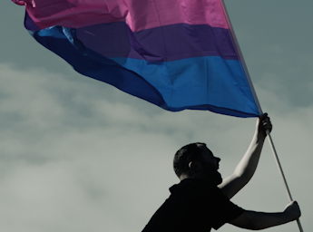 A picture of a man holding the Bisexuality flag.