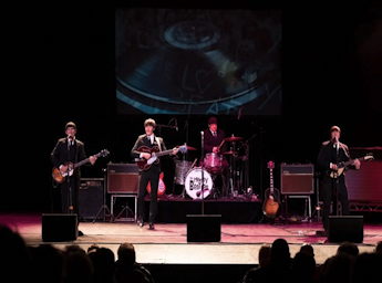 A picture of a band on stage looking like the young beatles.
