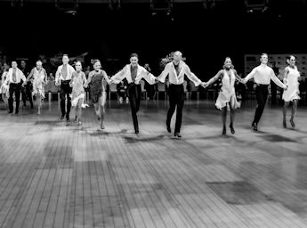 Black and white picture of a group of danceers performing in line.